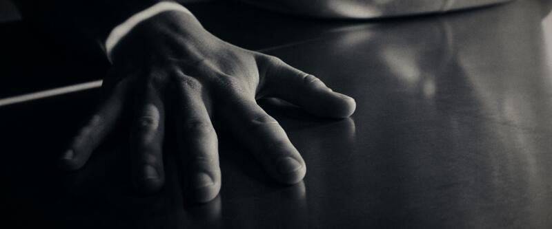 A hand spread flat on the cold surface of a metal table.